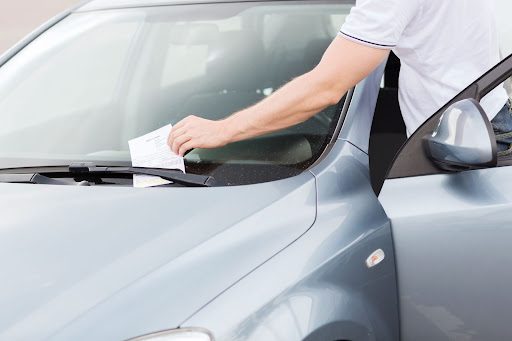 A parking ticket is placed on a car.