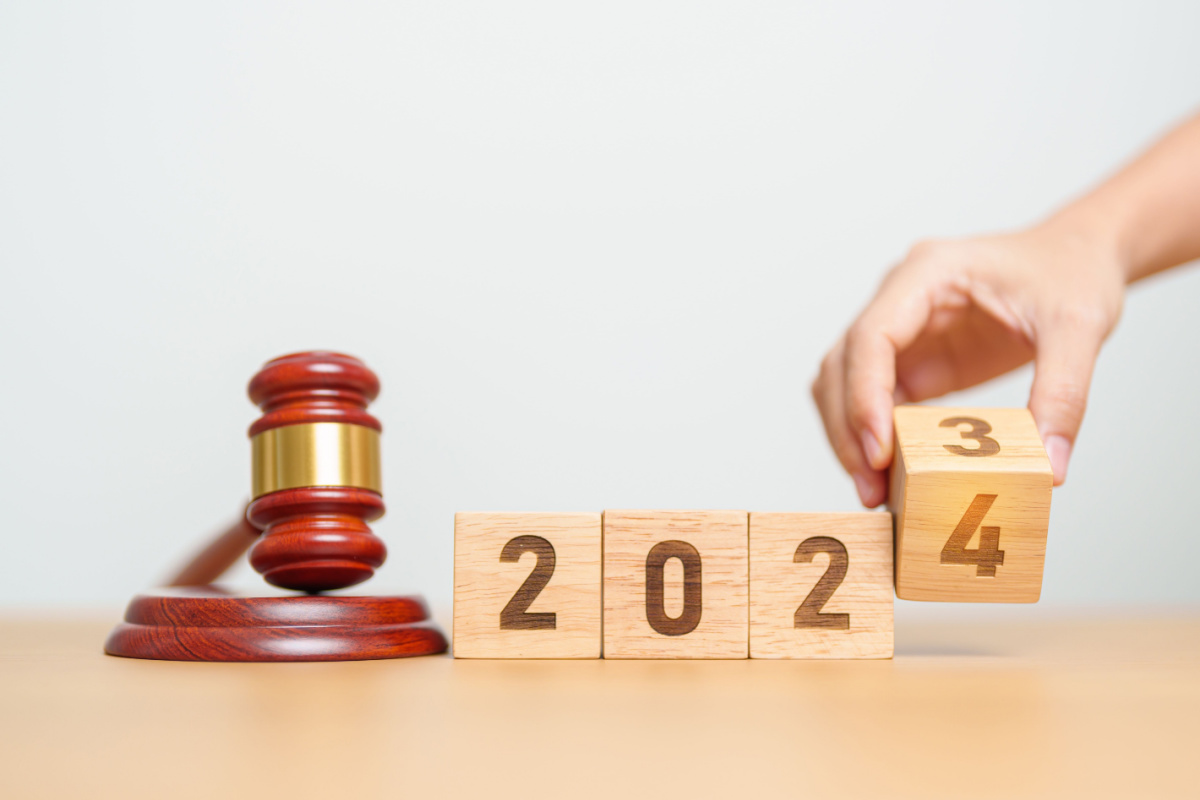 A person changes the year from 2023 to 2024. A gavel sits on the table next to the blocks.